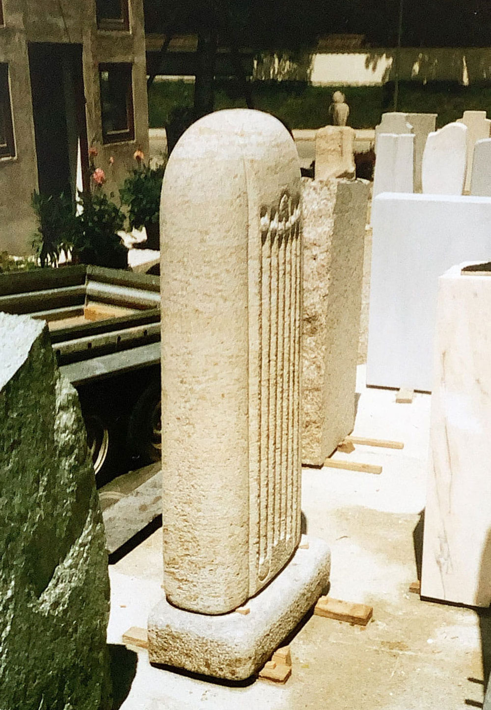Das Bild zeigt einen Grabstein aus Muschelkalk, seitlich gesehen in der Werkstatt stehend.