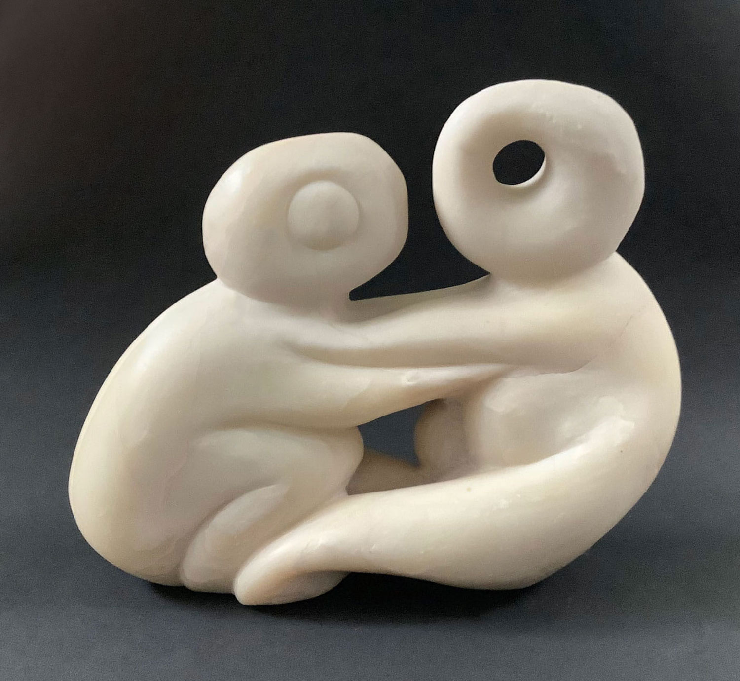 Die Skulptur aus Speckstein stellt 2 stilisierte Wesen dar, die sich umarmen