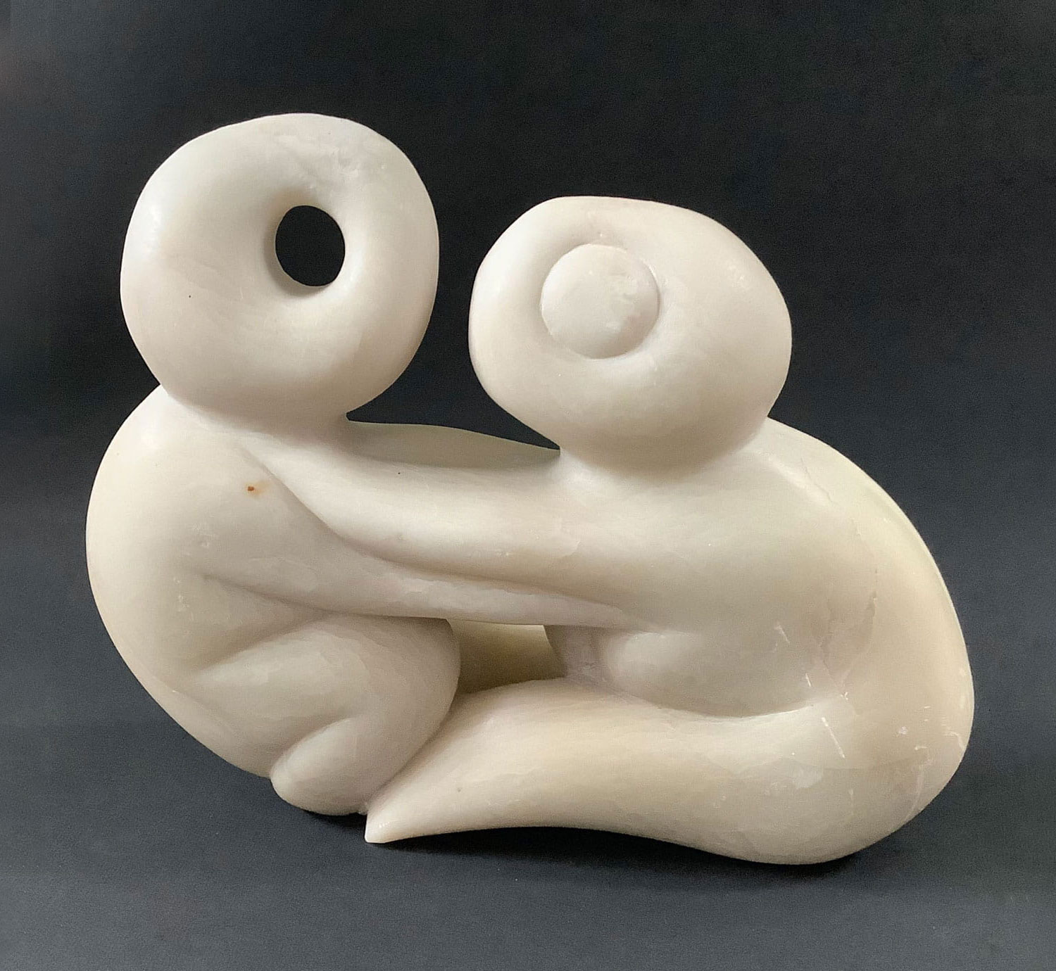 Die Skulptur aus Speckstein stellt 2 stilisierte Wesen dar, die sich umarmen