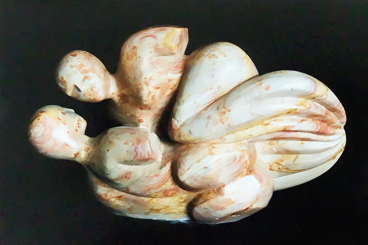 Die Skulptur aus Speckstein stellt in der Vordersicht zwei Frauen dar, die übereinander zu schweben scheinen.