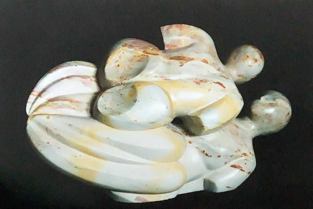 Die Skulptur aus Speckstein stellt in der Rückansicht zwei Frauen dar, die übereinander zu schweben scheinen.