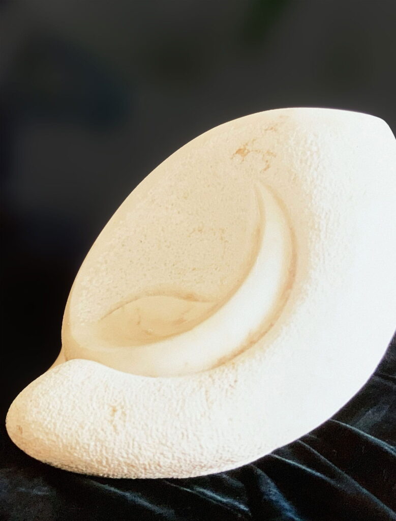 Skulptur aus Marmor. Draufsicht auf eine muschelförmige Skulptur mit glatten und rauen Oberflächen.
