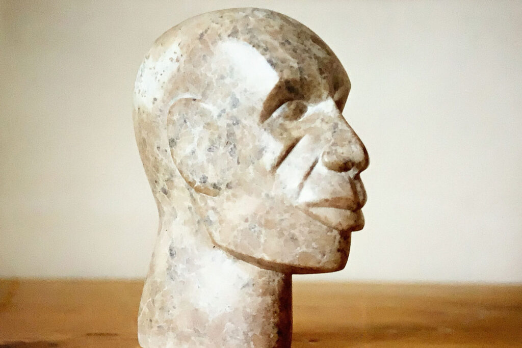 Skulptur eines Kopfes aus bräunlichem Speckstein sieht nach rechts.