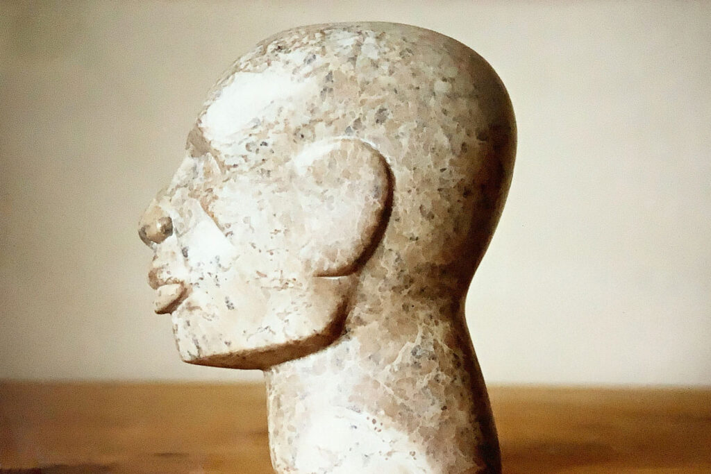 Skulptur eines Kopfes aus bräunlichem Speckstein sieht nach links.